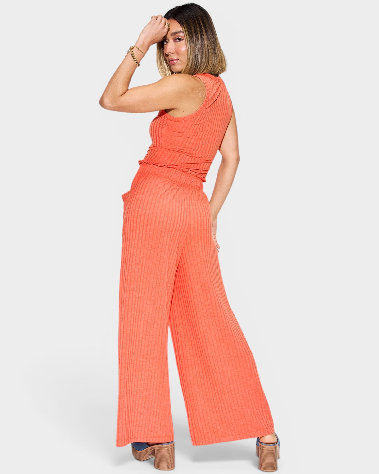 Woman wearing a bright orange jumpsuit on a white background