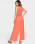 Woman wearing a coral jumpsuit on a white background