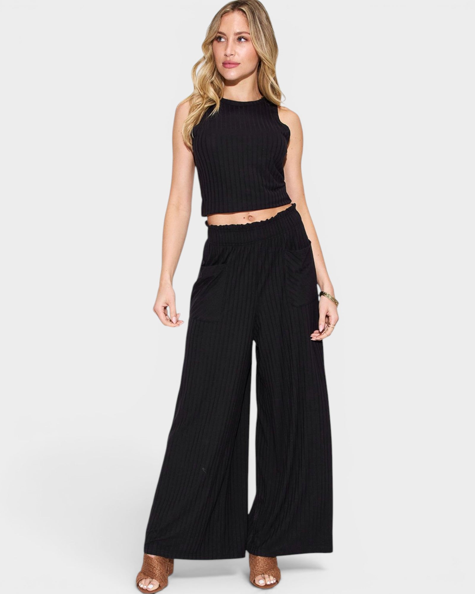 Woman wearing a black sleeveless top and wide-leg pants on a white background