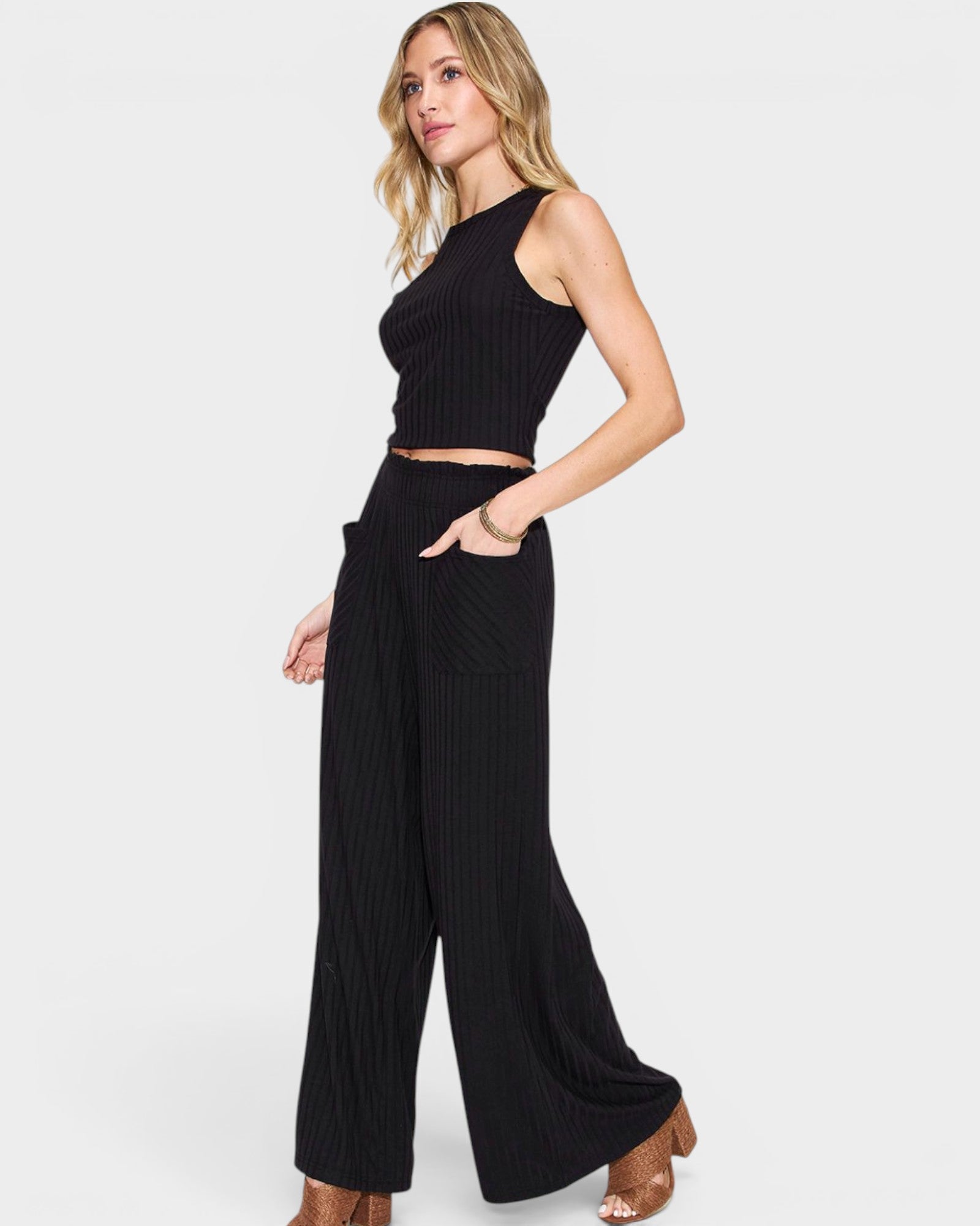 Woman wearing a black sleeveless top and wide-leg pants on a white background