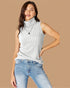Woman wearing a sleeveless ribbed sweater and jeans on a beige background