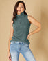 Woman wearing a green ribbed sleeveless sweater and blue jeans against a beige background