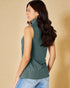 Woman wearing a green ribbed sleeveless sweater against a beige background