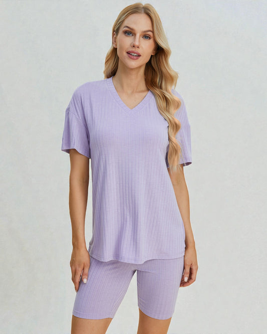 Woman wearing a light purple pajama set on a plain background