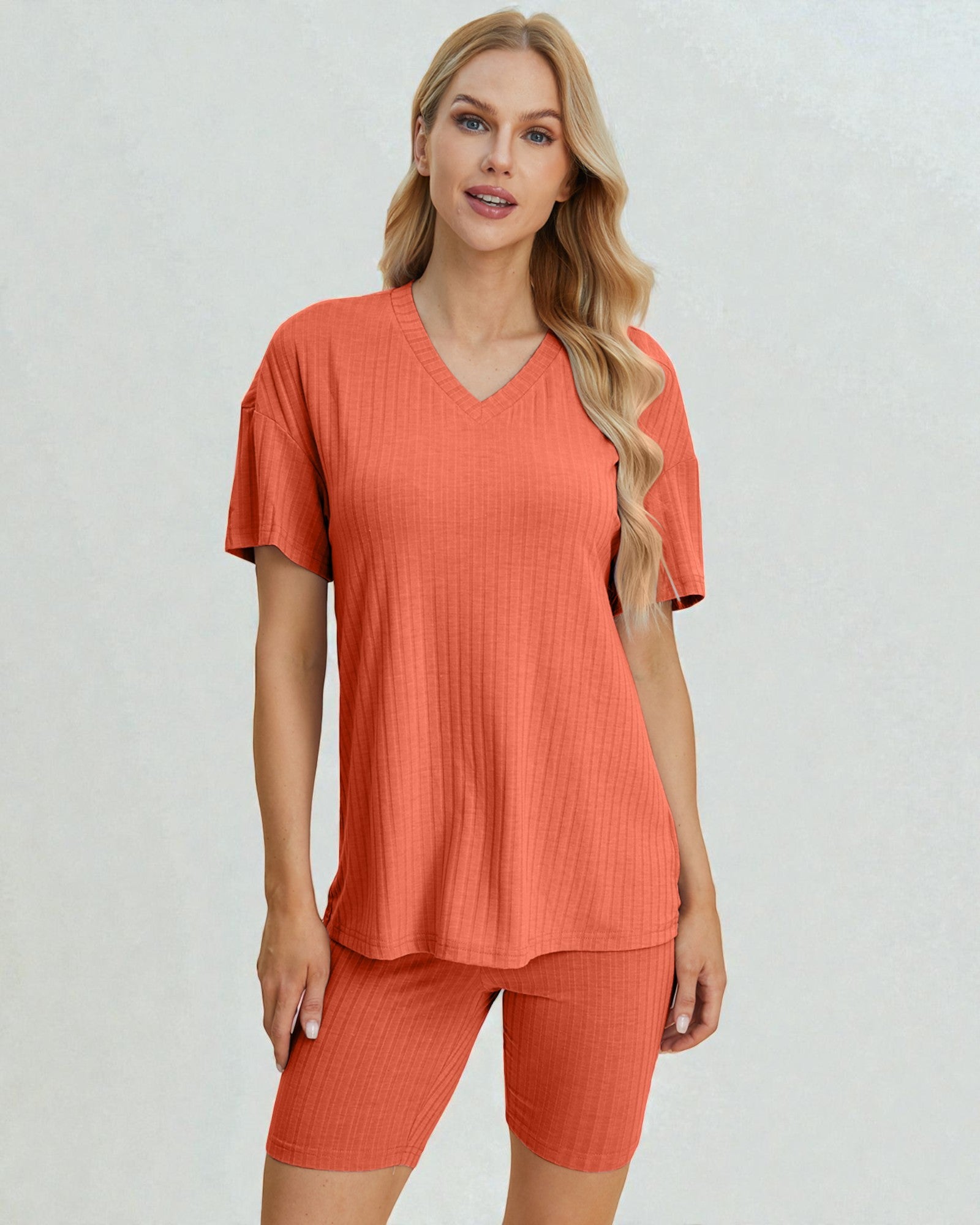 Woman wearing a coral-colored outfit on a plain background