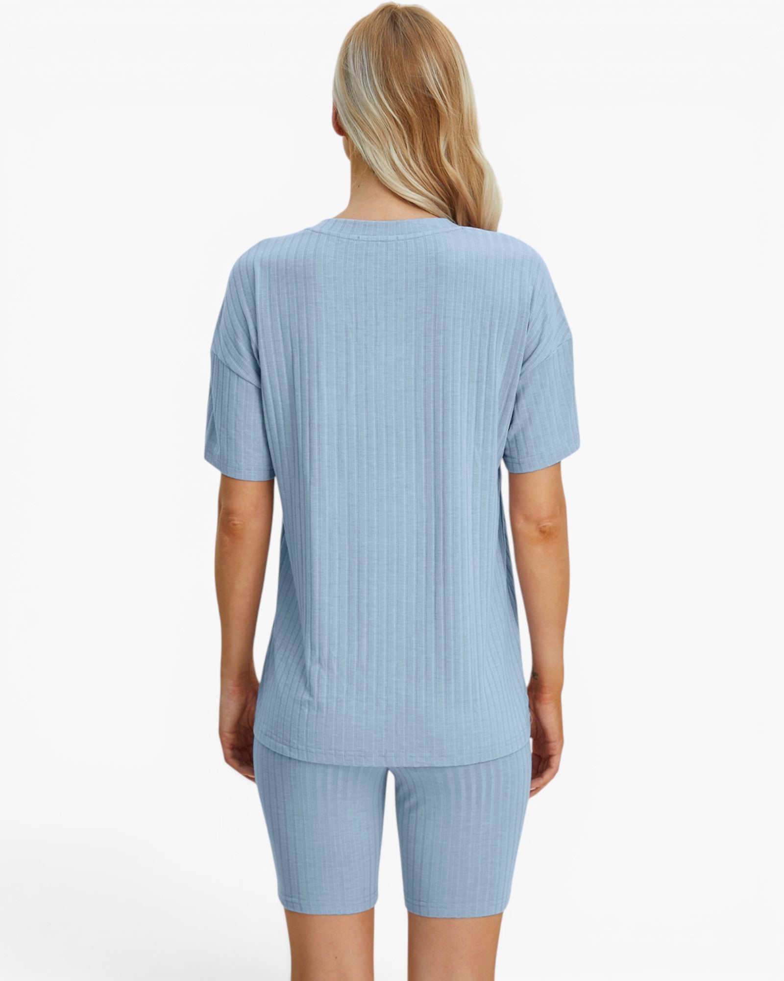 A woman viewed from the back wearing a light blue ribbed short-sleeve top and matching ribbed biker shorts against a plain white studio background.