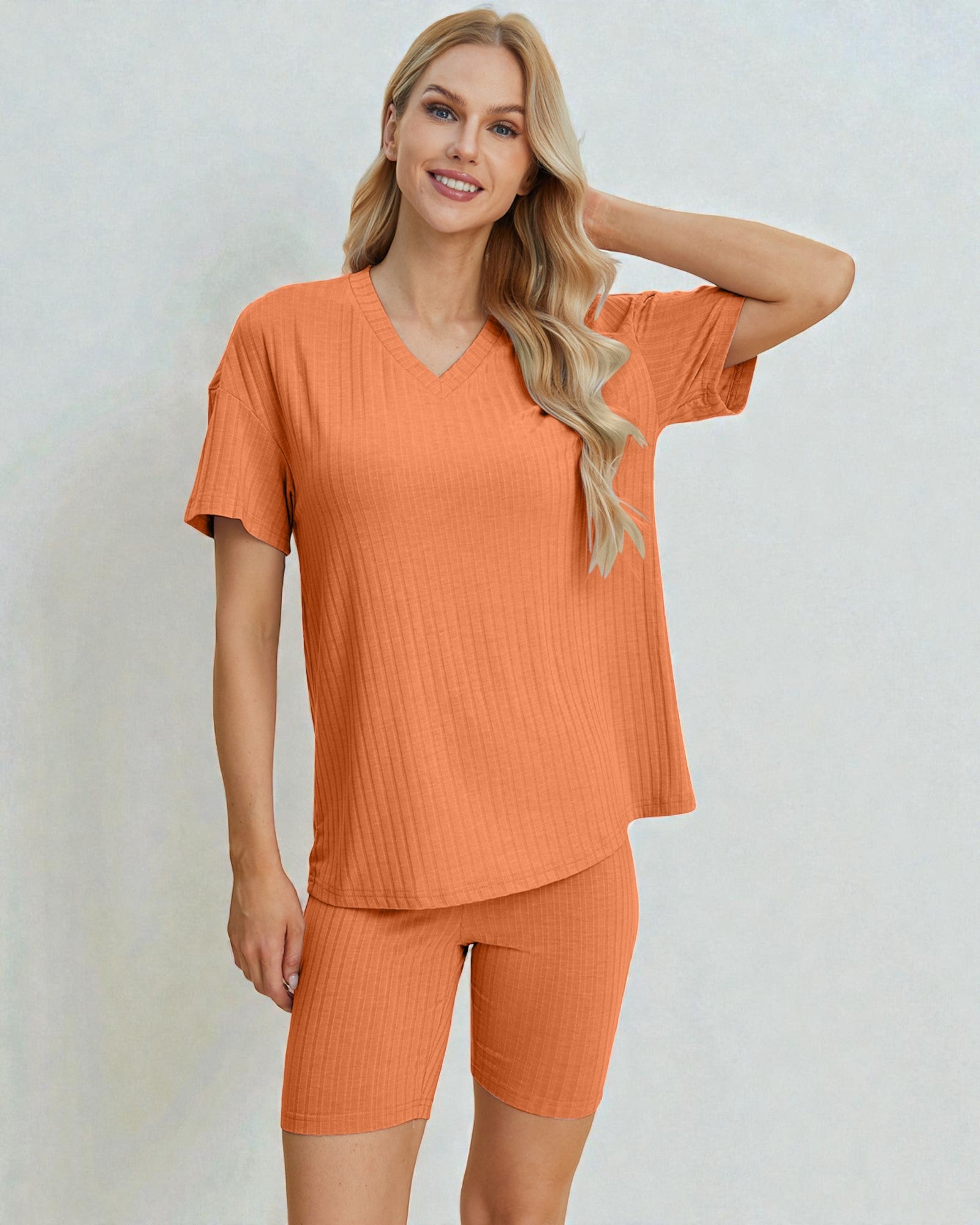 Woman wearing an orange ribbed outfit on a light gray background