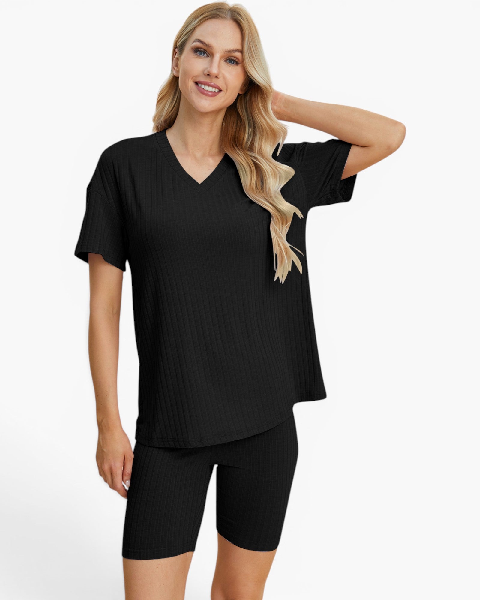 A woman modeling a black short-sleeve V-neck ribbed top with matching black biker shorts against a plain light gray studio background.