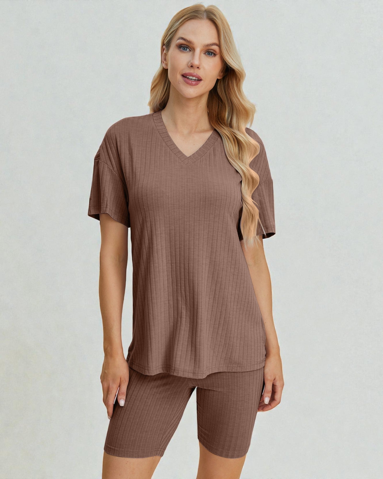 Woman wearing a brown ribbed top and shorts set on a light gray background