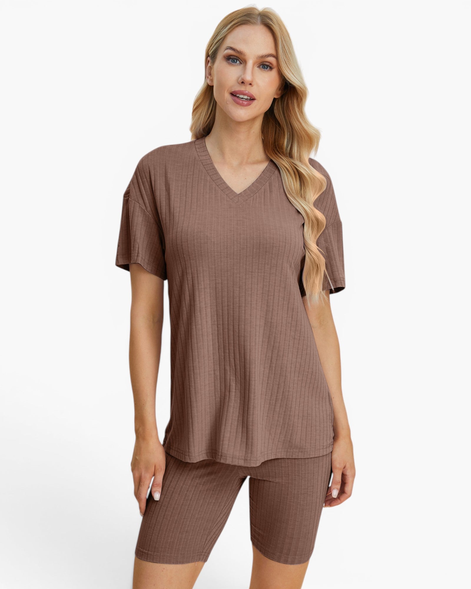 A woman modeling a matching ribbed lounge set consisting of a short-sleeve V-neck top and matching biker shorts in a warm taupe-brown color, set against a plain white studio background.