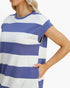 A close-up of a woman wearing a short-sleeve tunic top with horizontal blue and white stripes, set against a plain white background.