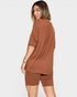 Woman wearing a brown t-shirt and shorts set on a white background