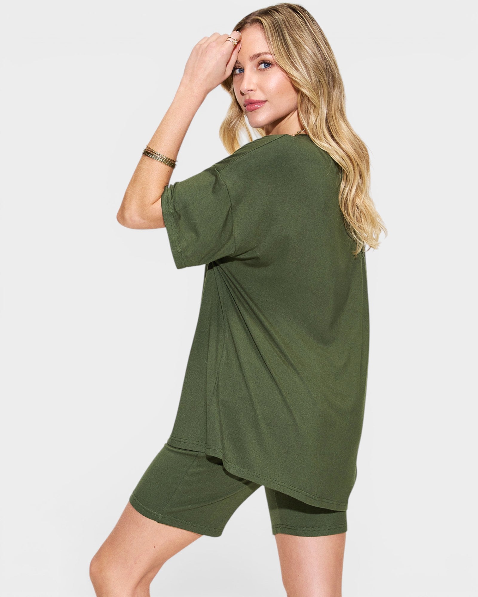 Woman wearing an olive green oversized t-shirt and shorts on a white background