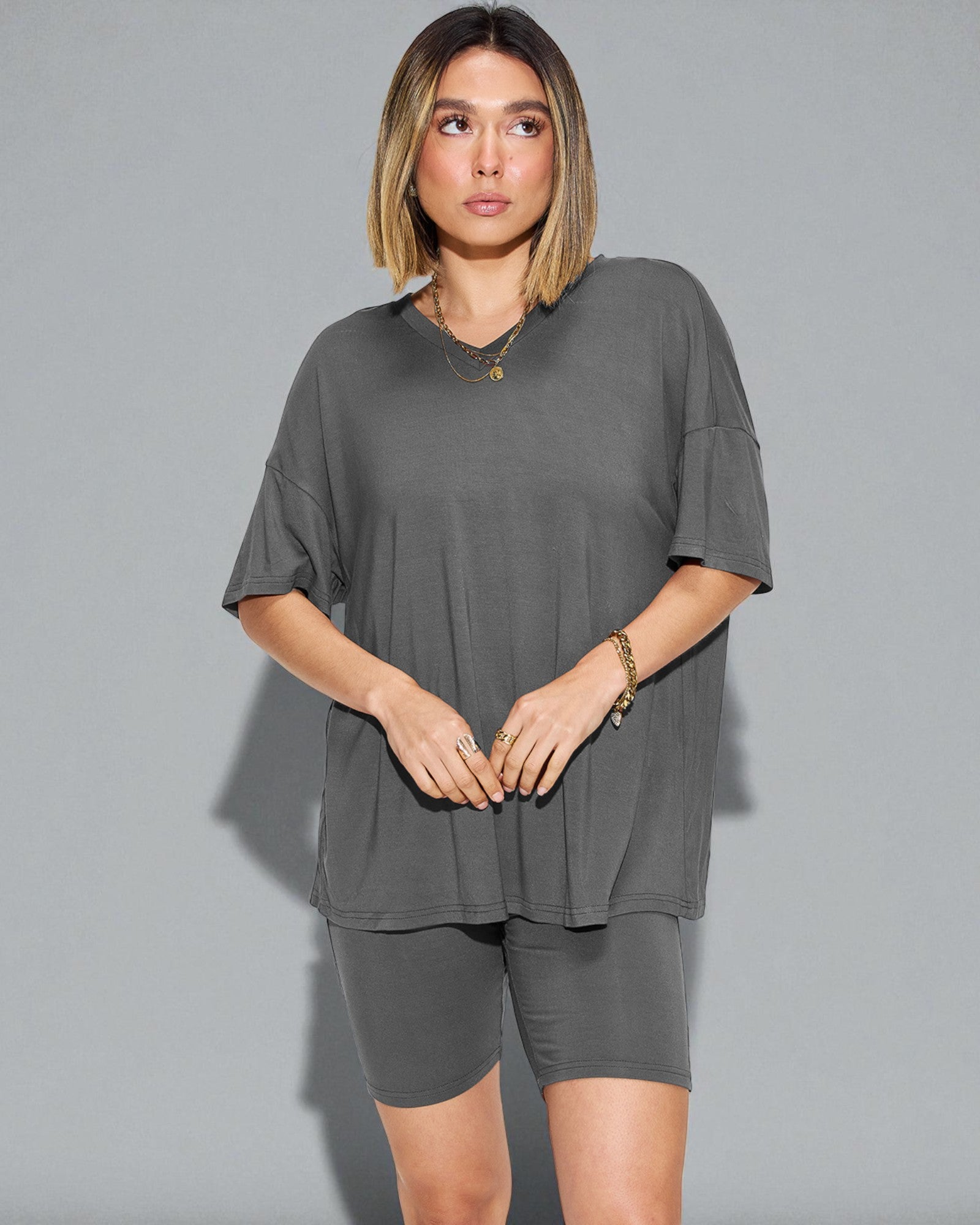 Woman wearing a gray oversized t-shirt and shorts set against a plain background