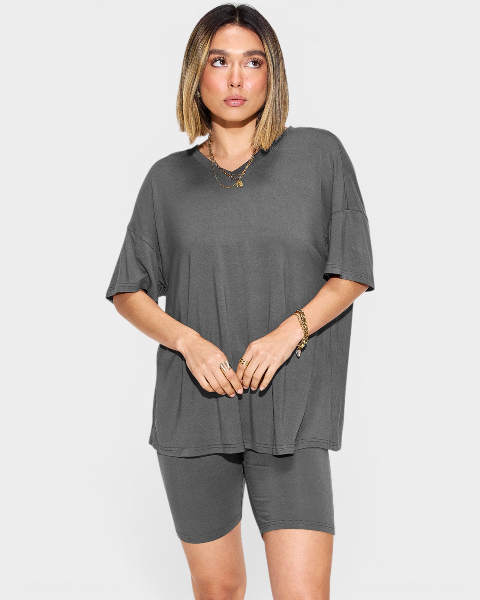 Woman wearing a gray oversized t-shirt and shorts set on a white background