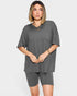 Woman wearing a gray oversized t-shirt and shorts set on a white background