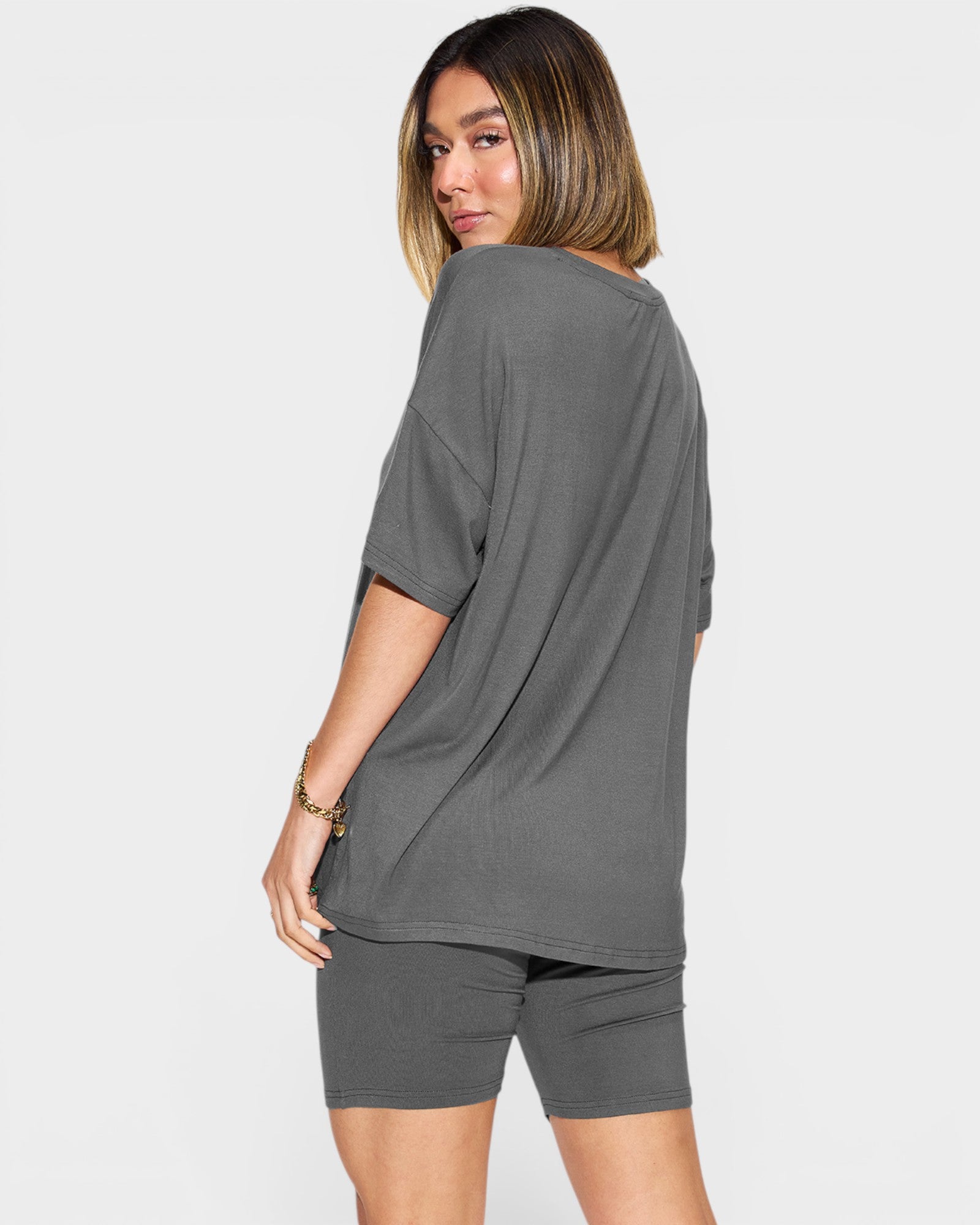 Woman wearing a gray oversized t-shirt and shorts set on a white background