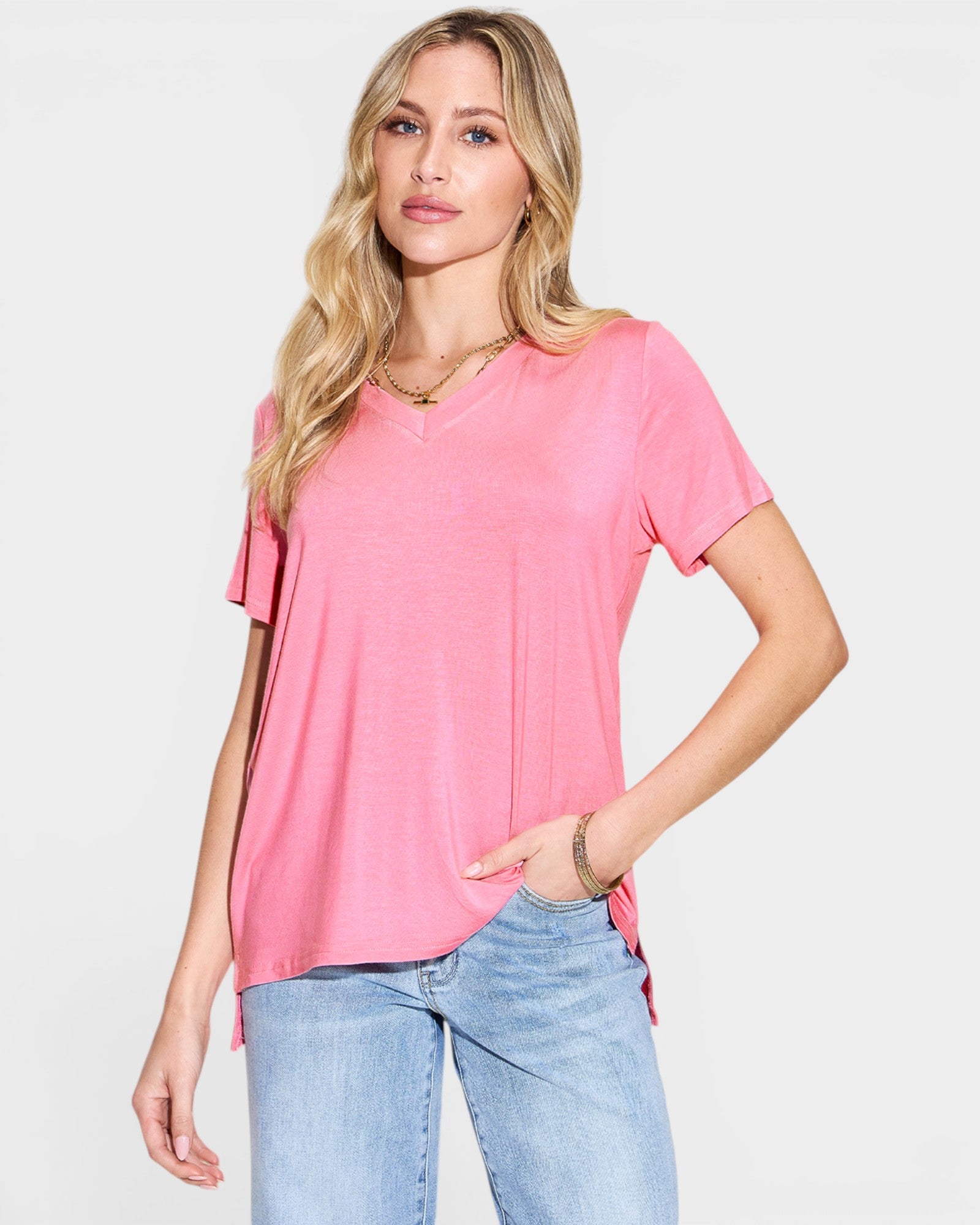 Woman wearing a pink t-shirt and light blue jeans on a white background