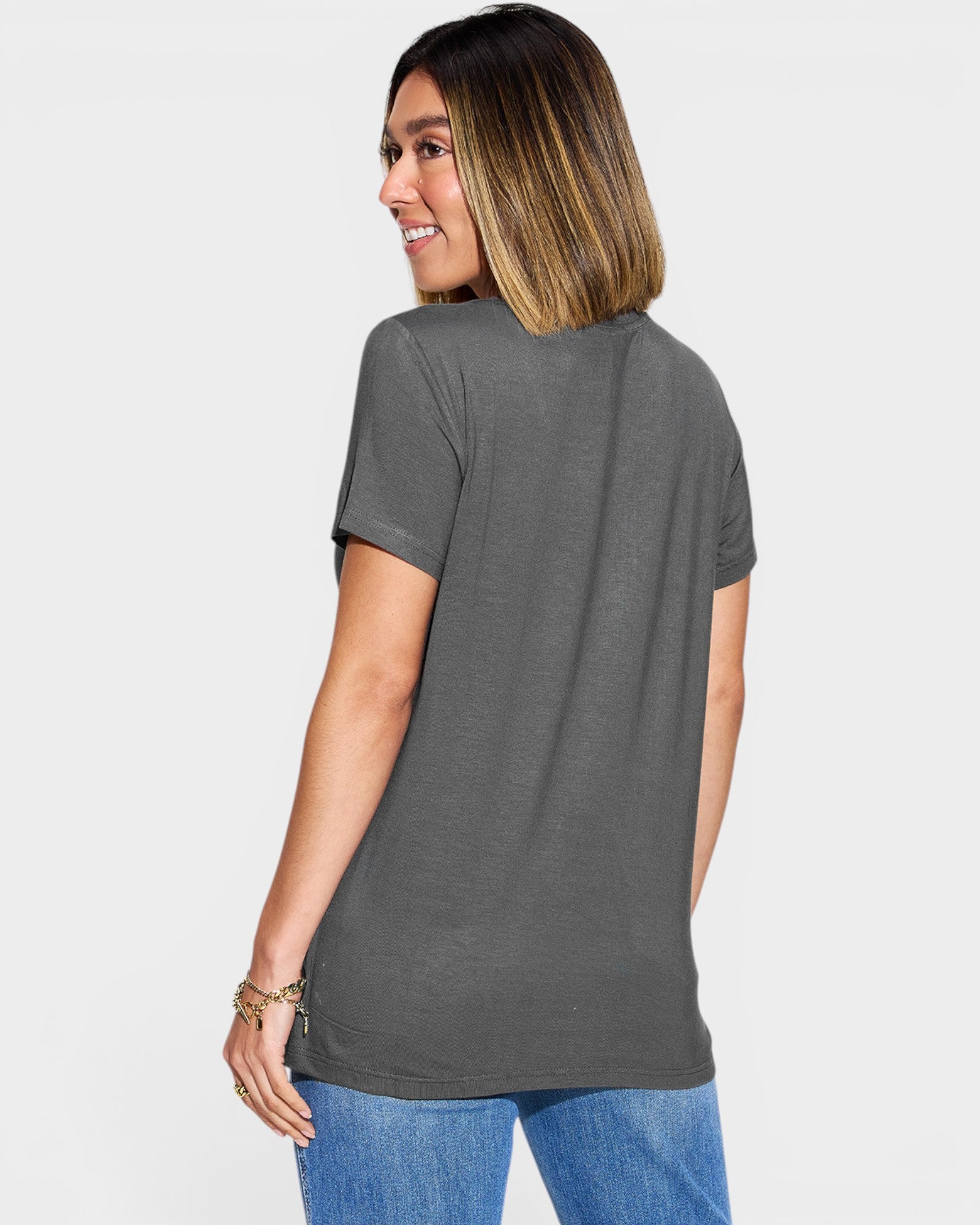 Woman wearing a gray t-shirt and blue jeans on a white background