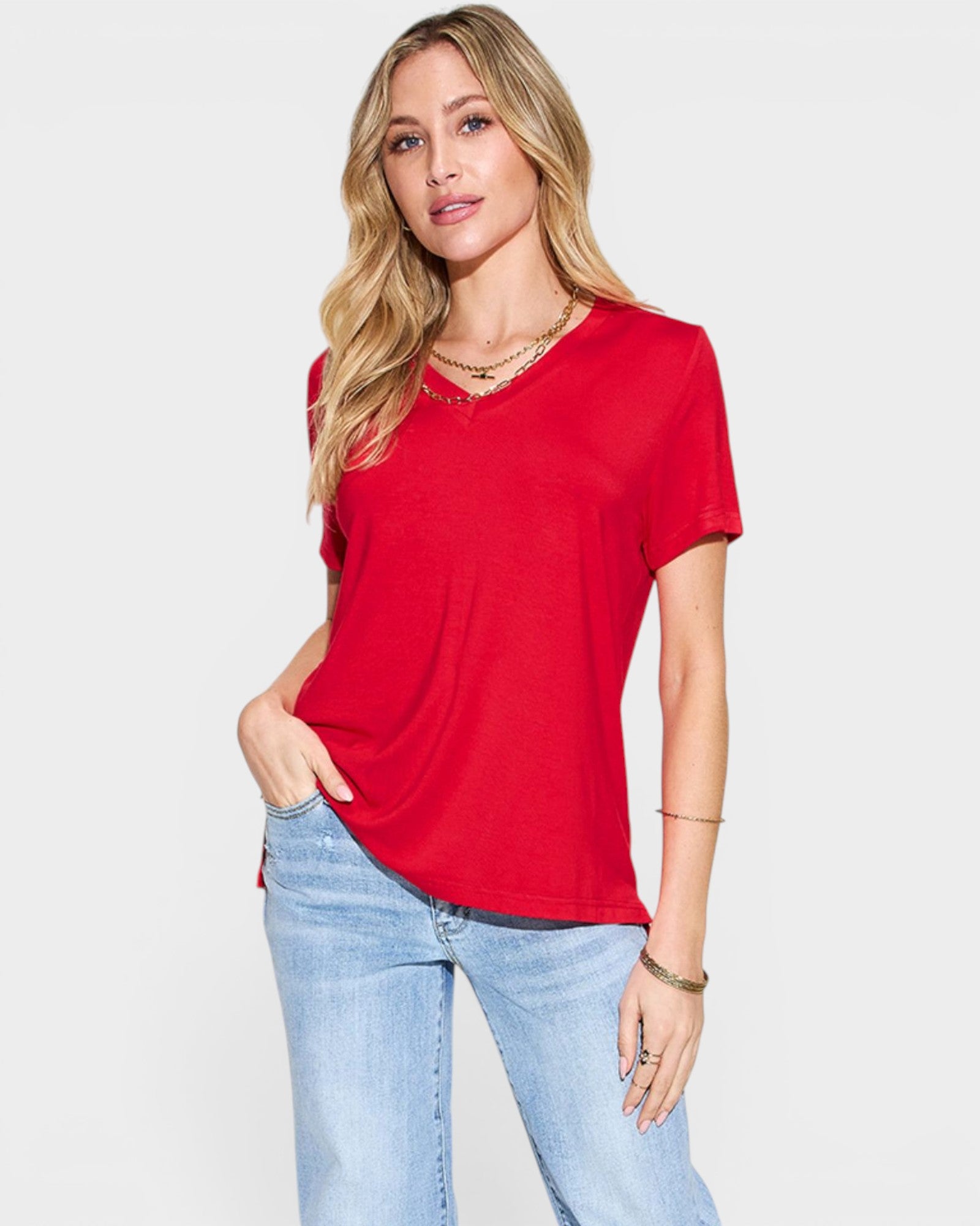 Woman wearing a red t-shirt and light blue jeans on a white background