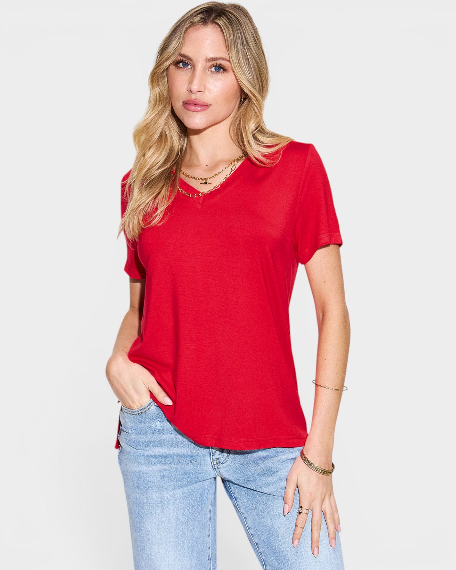 Woman wearing a red t-shirt and light blue jeans on a white background
