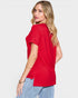 Woman wearing a red t-shirt and light blue jeans on a plain background