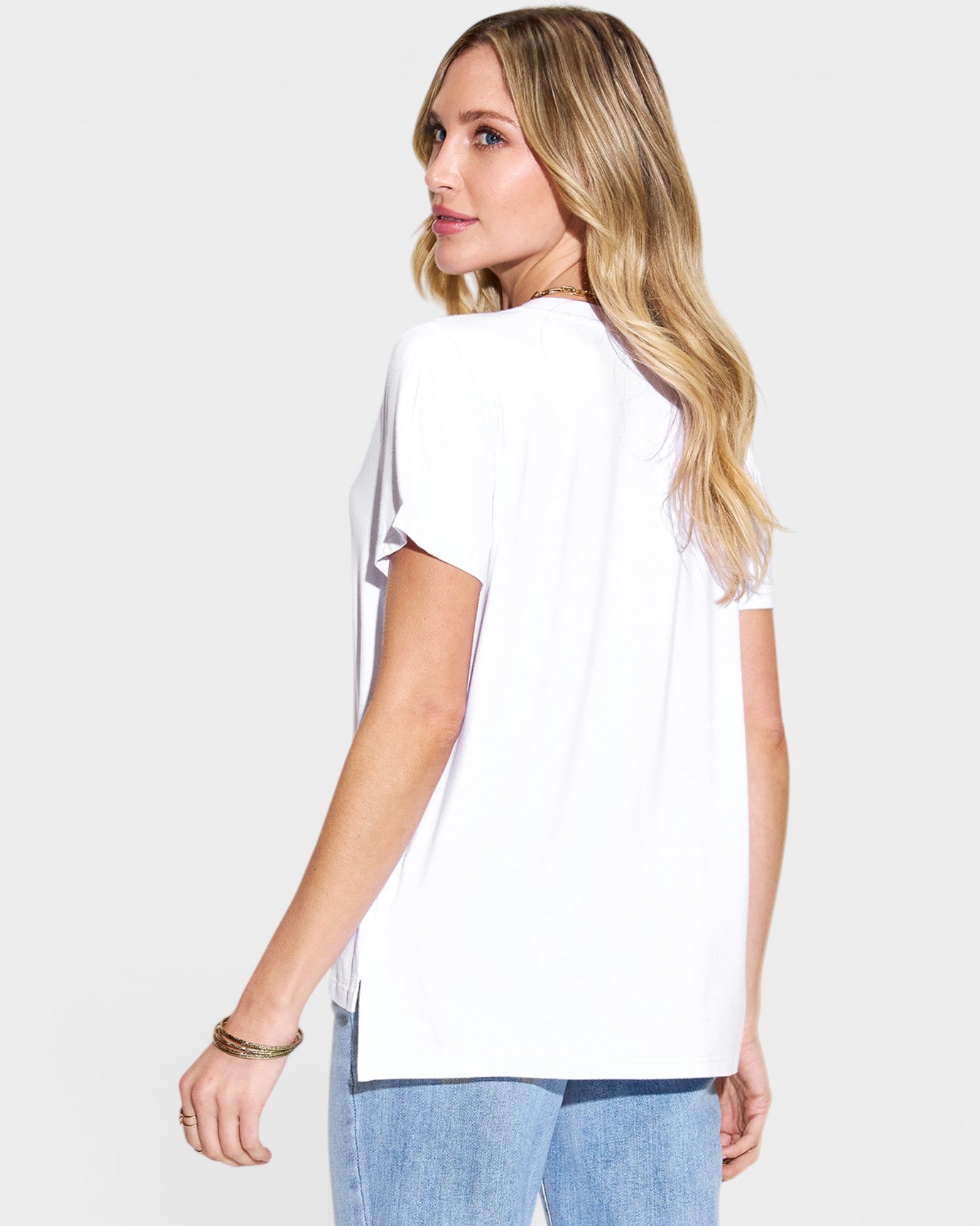 Woman wearing a white t-shirt and blue jeans on a plain background