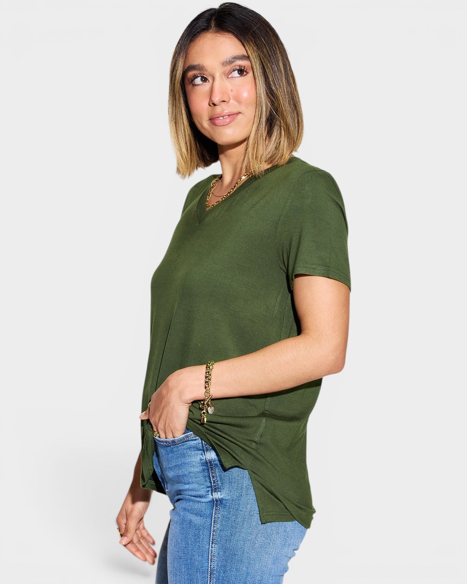 Woman wearing an olive green t-shirt and blue jeans on a white background