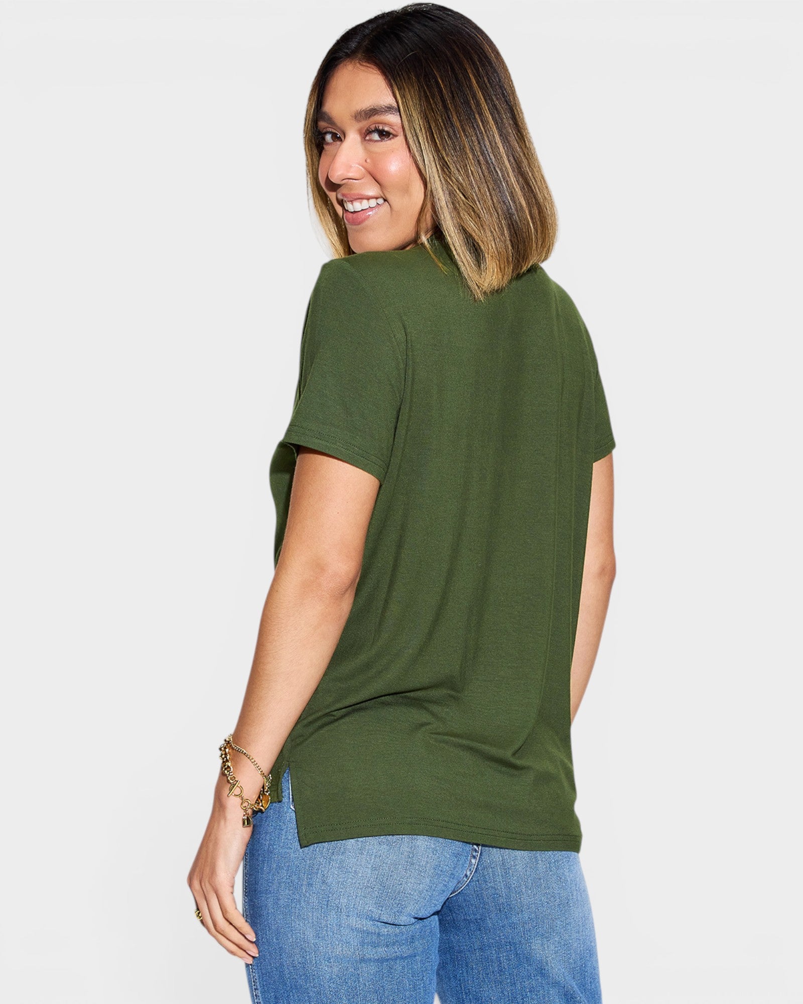 Woman wearing an olive green t-shirt and blue jeans on a white background