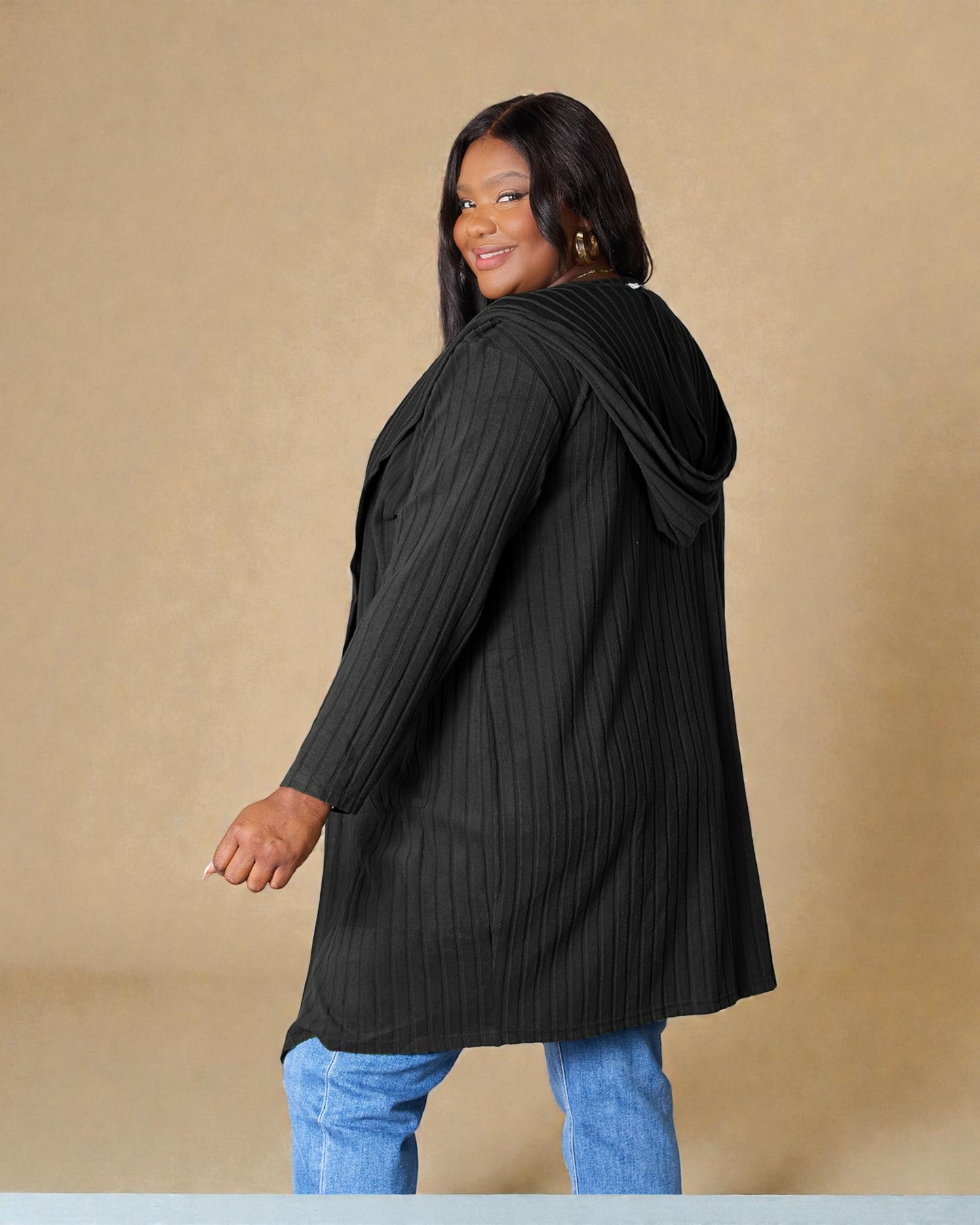 Woman wearing a black ribbed sweater against a beige background