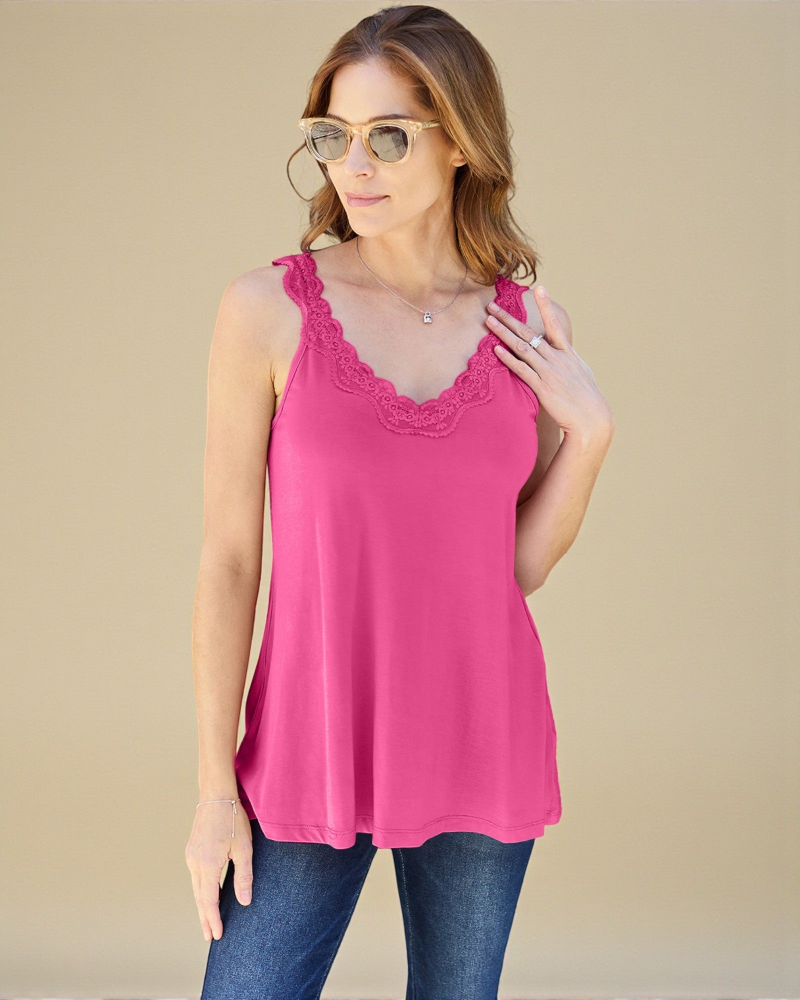 Woman wearing a pink tank top with lace details on a beige background