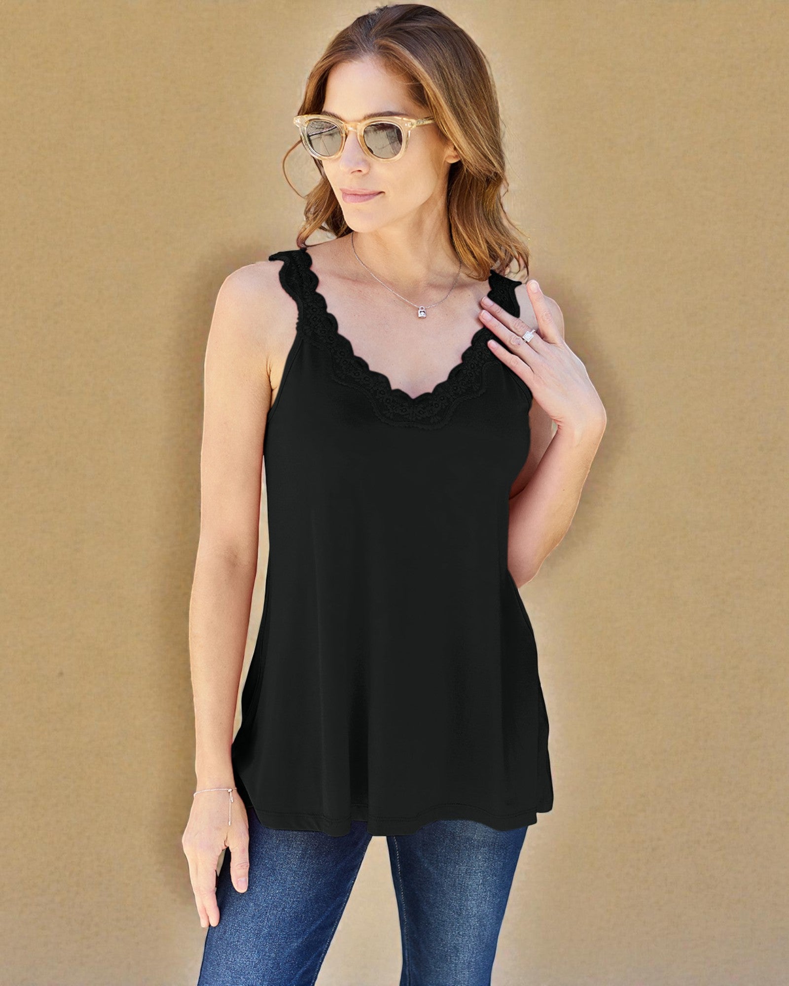 Woman wearing a black tank top with lace details against a beige background