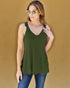 Woman wearing a green tank top with lace details against a beige background