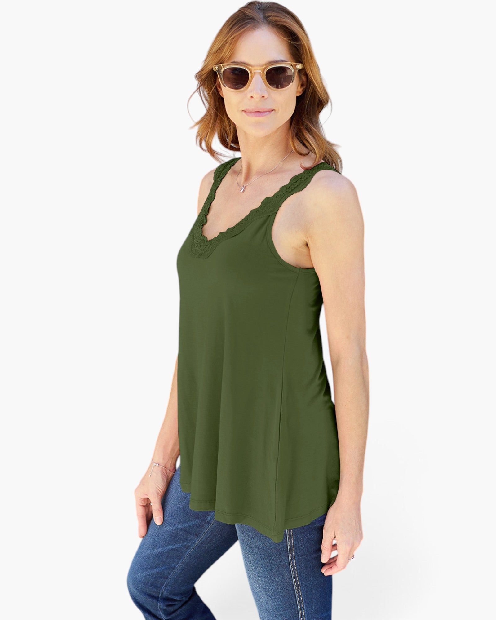 A woman modeling a sleeveless olive green tank top with a scalloped V-neckline, paired with blue jeans against a plain white background.