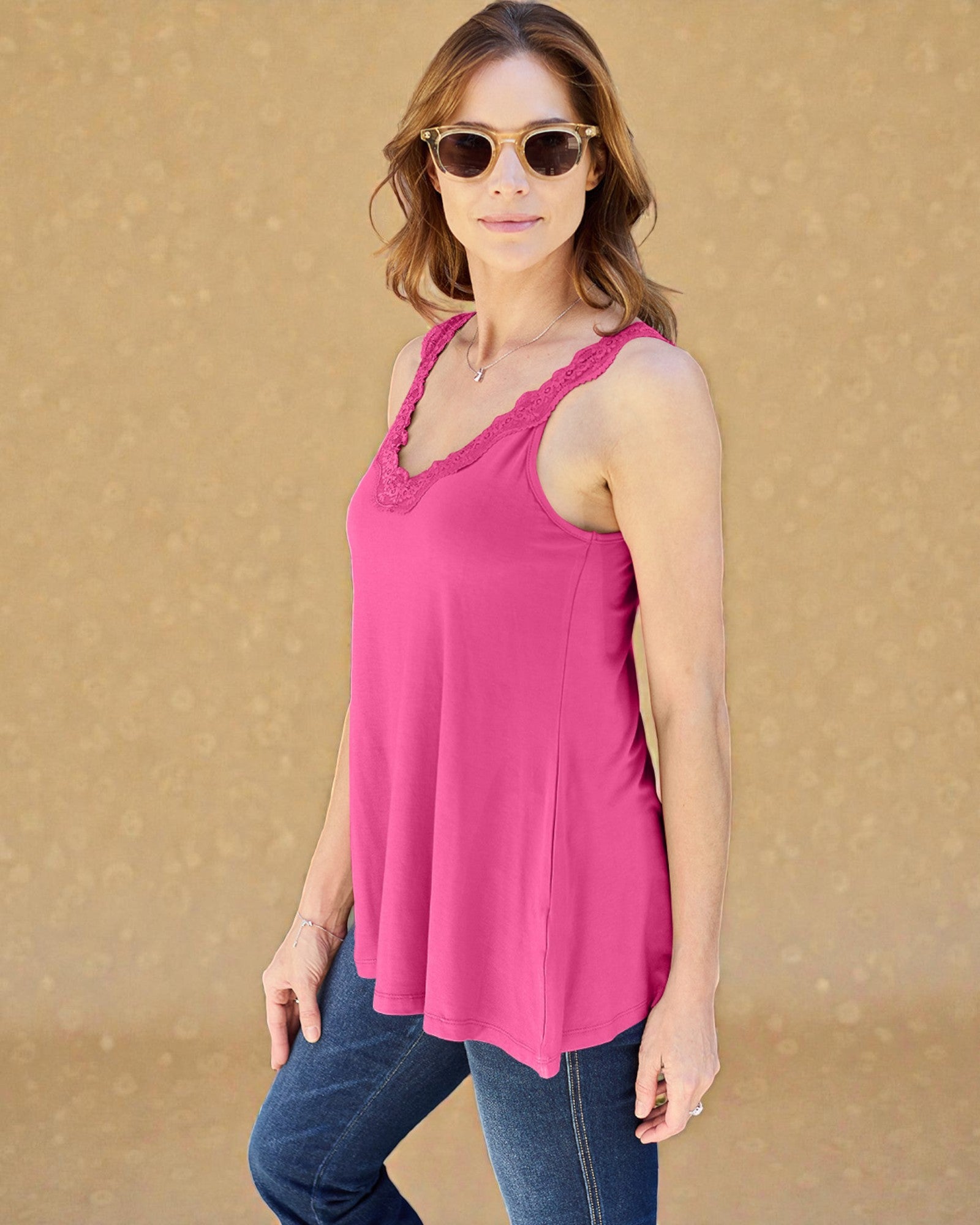 Woman wearing a pink tank top and sunglasses against a beige background