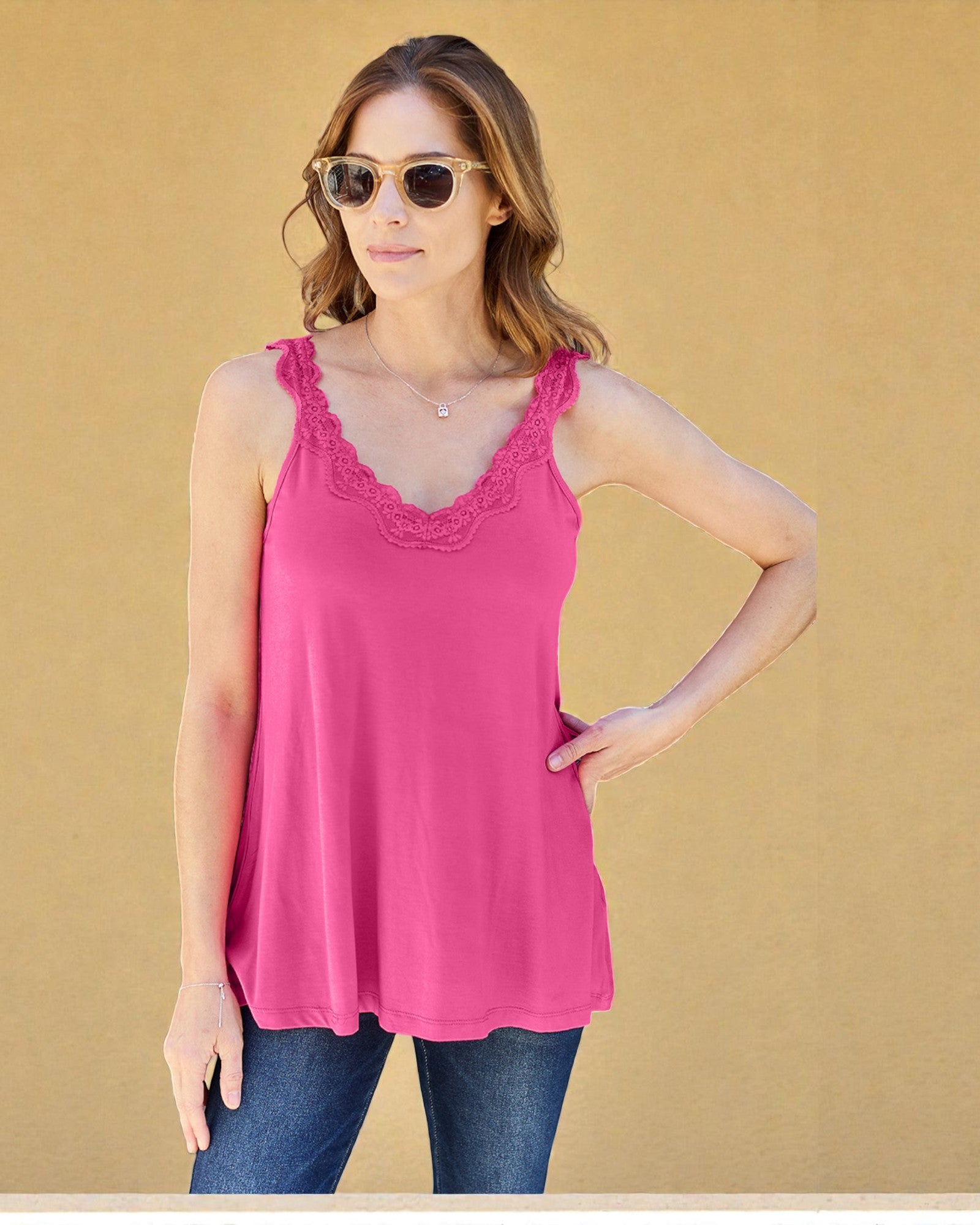 Woman wearing a pink tank top with lace details against a beige background