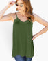 A woman wearing an olive green camisole tank top with thin straps and a scalloped lace neckline, paired with blue jeans and gold-framed sunglasses, against a plain white background.