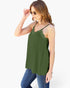 A woman wearing an olive green camisole top with thin straps and scalloped lace trim, paired with blue jeans, against a plain white background.