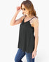 A woman wearing a black camisole top with thin straps and scalloped lace trim at the neckline, paired with blue jeans, against a plain white background.