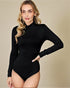 Woman wearing a black long-sleeve bodysuit against a beige background