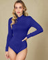 Woman wearing a blue long-sleeve bodysuit against a beige background
