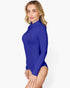 A woman modeling a royal blue long-sleeve mock neck bodysuit against a plain white studio background.