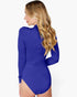 A woman with long wavy blonde hair is shown from the back wearing a royal blue long-sleeve bodysuit against a plain white background.