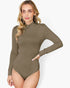 A woman modeling a long-sleeve, high-neck bodysuit in a solid taupe-brown color, set against a plain light gray background.