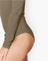 Close-up of a model wearing a long-sleeve high-cut bikini or swimsuit bottom in a muted taupe-brown color against a plain light background.
