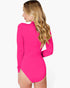 A woman wearing a bright hot pink long-sleeve bodysuit, shown from a side-back angle against a plain white studio background.