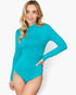 A woman modeling a bright turquoise long-sleeve mock neck bodysuit against a plain light gray background.