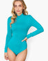 A woman modeling a bright turquoise long-sleeve mock neck bodysuit against a light gray studio background.