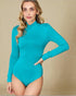 Woman wearing a teal long-sleeve bodysuit against a beige background