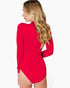 A woman with long wavy blonde hair is shown from the back wearing a bright red long-sleeve bodysuit with a high mock neck and a side slit, against a plain white background.